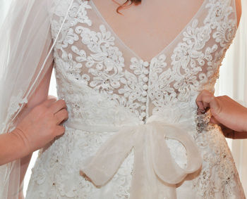 Cropped hands adjusting bride dress during wedding