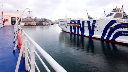 Boats moored at harbor against sky in city