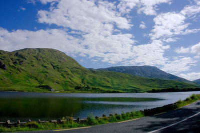 Scenic view of lake by mountains against sky