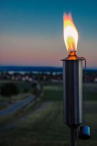 Close-up of lit candles on beach against sky during sunset