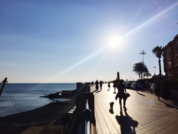 People on beach against clear sky during sunset