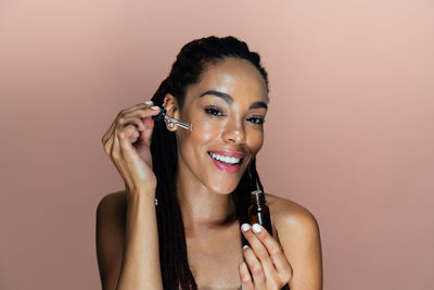 Portrait of young woman applying make-up against white background