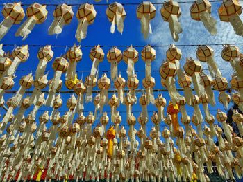 Low angle view of lighting equipment hanging against blue sky