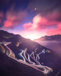 High angle view of light trails on mountain road against cloudy sky at night