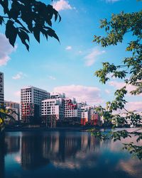 Buildings by lake against sky in city