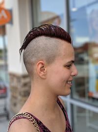 Side view of smiling young woman looking away by glass window