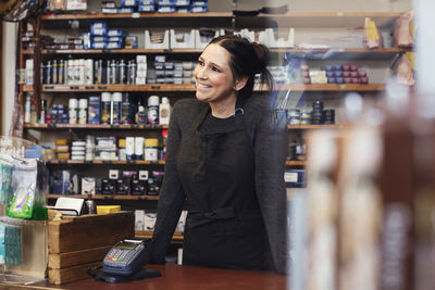 Smiling woman looking away while standing in repair shop