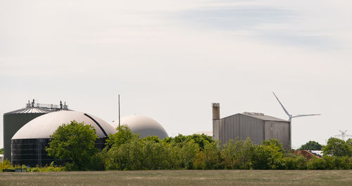 Plants growing by factory against sky