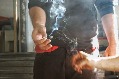 Cropped image of people holding burning cigarette