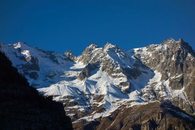 Scenic view of snowcapped mountains against clear blue sky