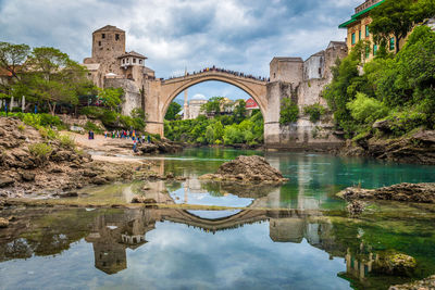 Arch bridge over river against cloudy sky