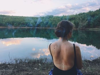 Rear view of man standing by lake against sky