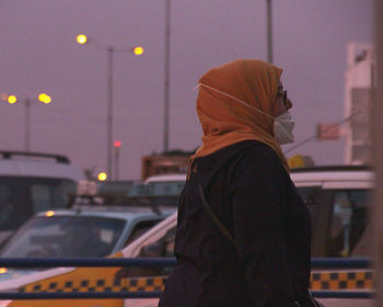 Side view of man standing in city at night