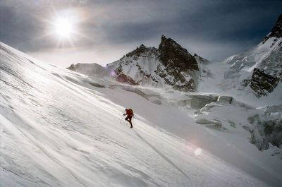 Man skiing on snowcapped mountain against sky