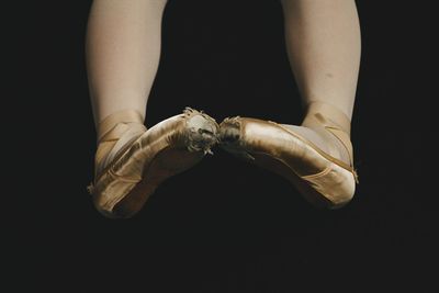 Low section of female ballet dancer with torn shoes against back background