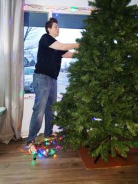 Young man standing in illuminated christmas tree