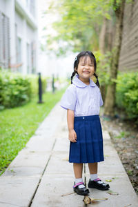 Portrait of smiling schoolgirl standing on footpath