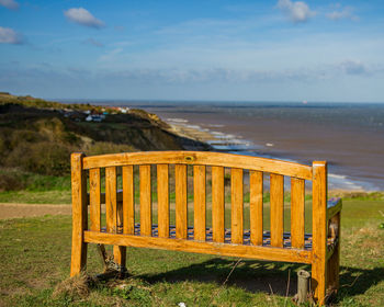 Empty seats on beach against sky