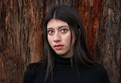 Portrait of a beautiful young woman with tree trunk