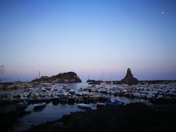 Boats in sea against clear sky at sunset