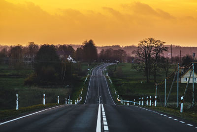 Road amidst trees against sky during sunset