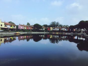 Reflection of houses and trees in lake against sky