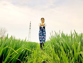 Boy on grassy field against sky