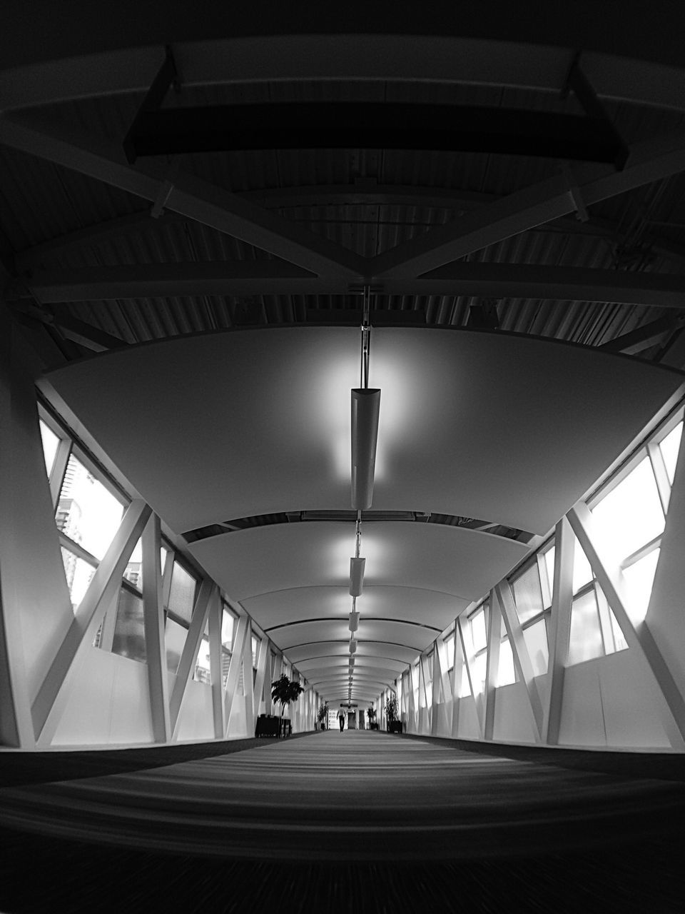 indoors, ceiling, architecture, built structure, illuminated, lighting equipment, diminishing perspective, the way forward, low angle view, modern, vanishing point, in a row, incidental people, corridor, electric light, empty, connection, transportation, hanging, no people
