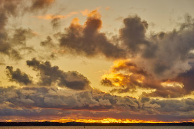 A colorful sunset on the baltic sea with clouds illuminated by the sun setting over the horizon.
