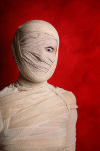 Portrait of woman wrapped with bandages against red background