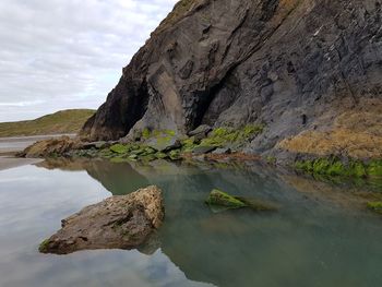 Rock formation by sea against sky