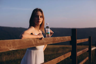 Portrait of woman standing by railing against sky