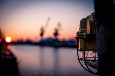 Close-up of old light at harbor during sunset