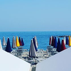 Deck chairs on beach against clear blue sky