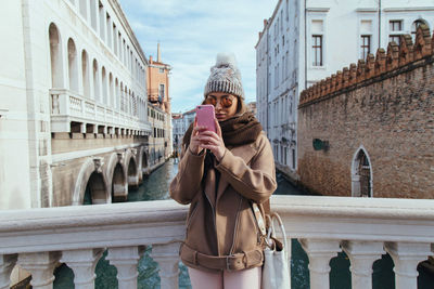Woman standing with mobile phone in city