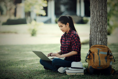 Young woman using mobile phone while sitting outdoors