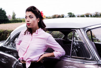 Beautiful woman standing by car against sky