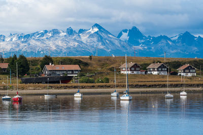 Houses by snowcapped mountains against sky during winter