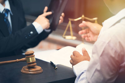 Midsection of lawyer and client discussing on table