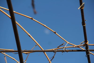 Low angle view of metal fence against blue sky