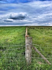 Scenic view of grassy field against cloudy sky