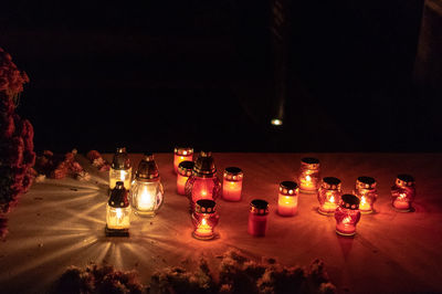 Illuminated lamps on grave at night