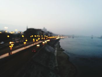 Illuminated city by sea against clear sky