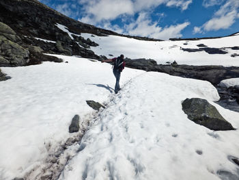 Rear view of man hiking on snow covered mountain