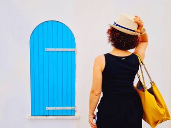 Tourist from behind with hat next to a typical house in alghero sardinia