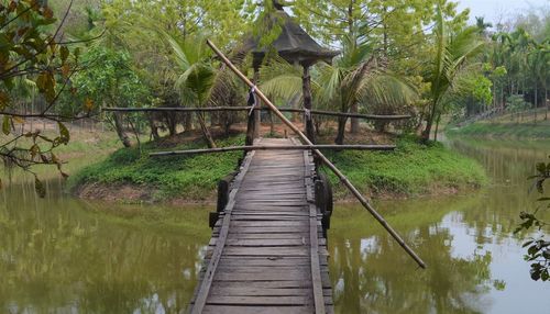 Footbridge over lake against trees