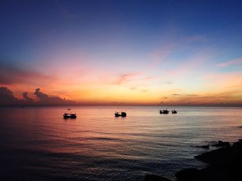 Boats in calm sea at sunset