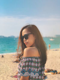 Young woman wearing sunglasses on beach against sky