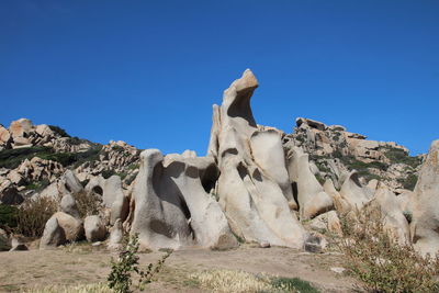 Low angle view of rocks on rock against blue sky
