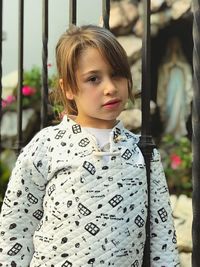 Portrait of cute girl standing against fence